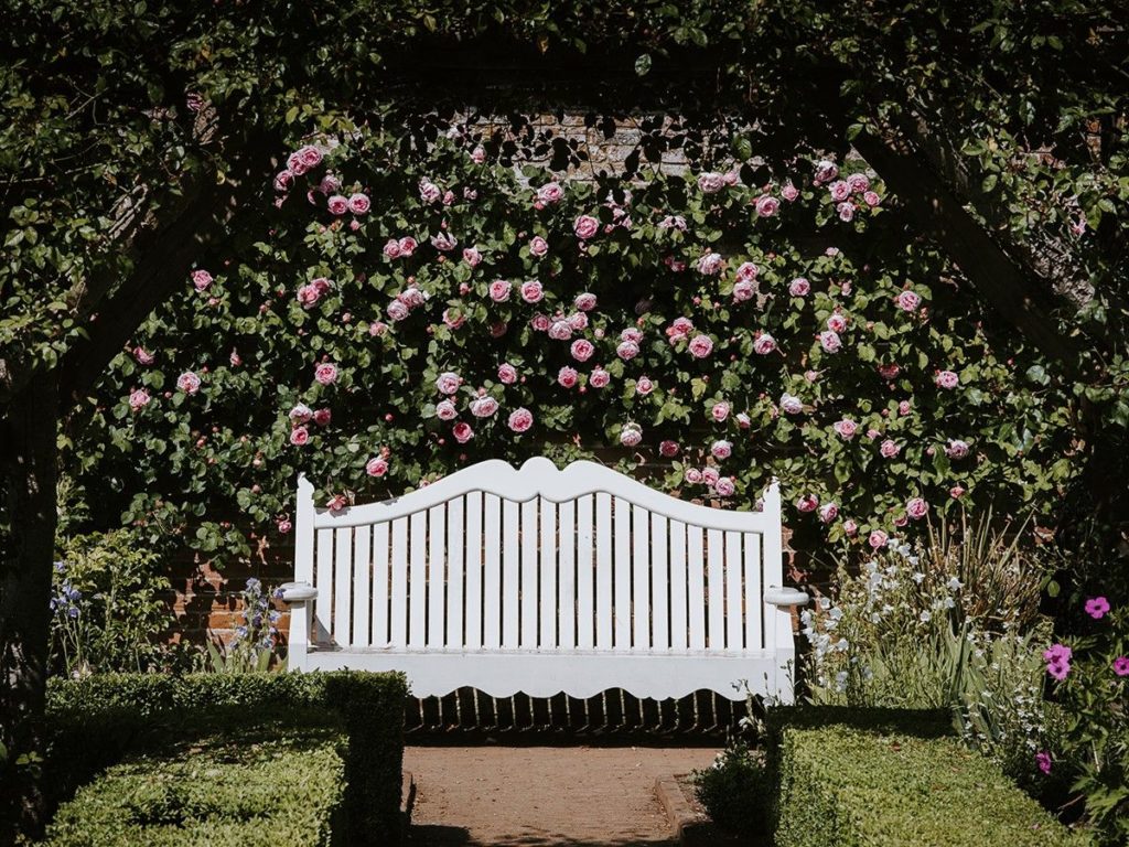 weiße Sitzbank aus Holz im Garten